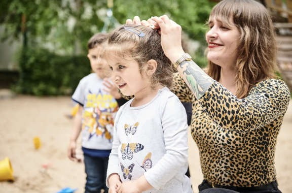 Eine Frau macht einem kleinen Kind einen Zopf