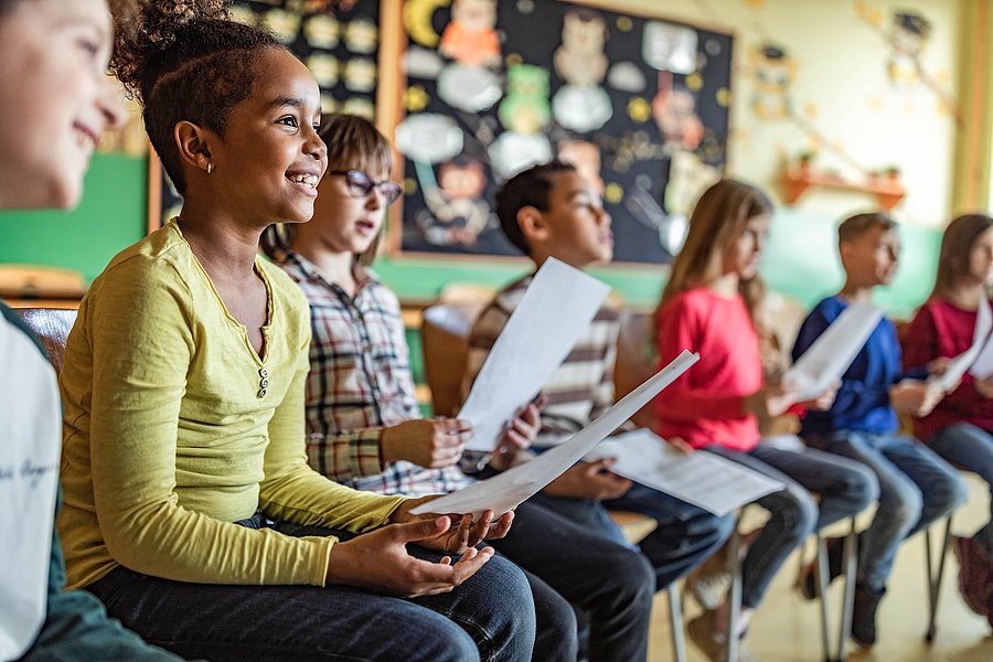 Kindergarten- oder Schulkinder sitzen in einer Stuhlreihe oder Stuhlkreis